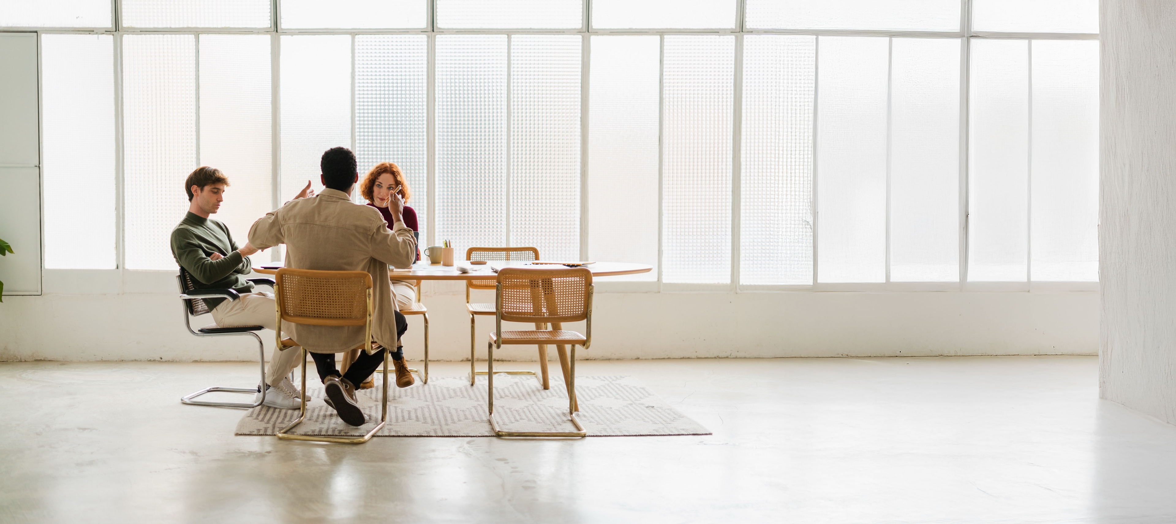 Three people at desk in large white room